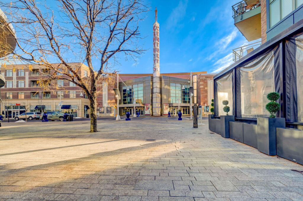 Outdoor shopping district with several storefronts, restaurants, and a movie theater