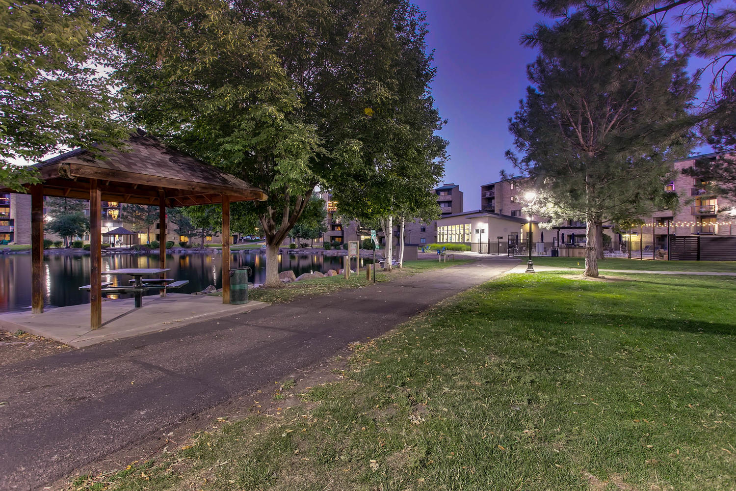 Walking trail around the lake with large trees and covered sitting area