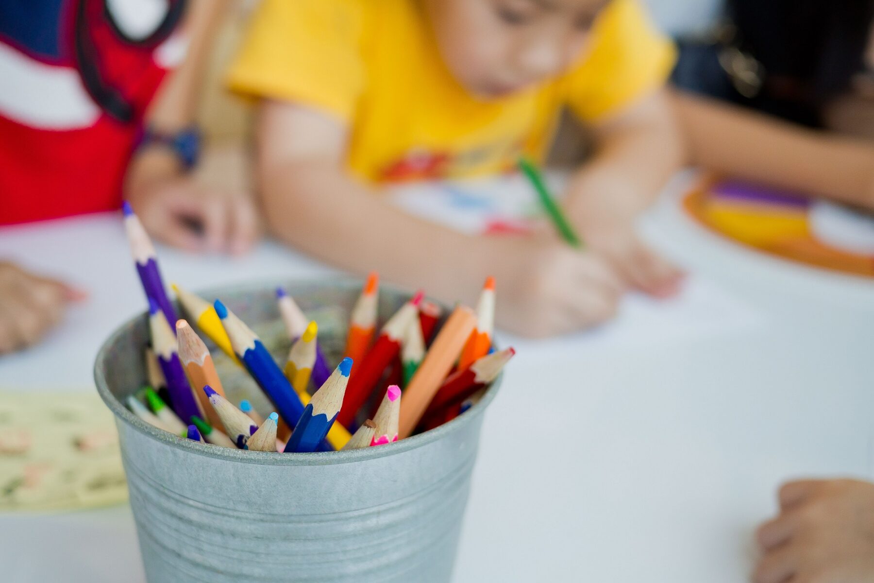 Kids at a table using colored pencils to draw